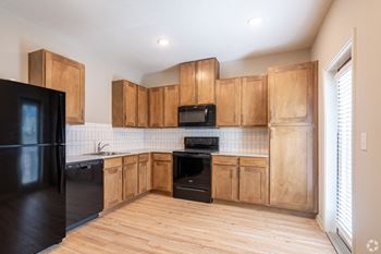 an empty kitchen with wooden cabinets and black appliances